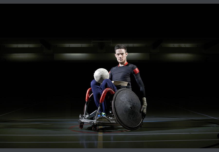 Wheelchair rugby player with ball in lap.