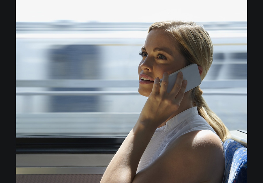 Young business lady travelling on train using mobile phone