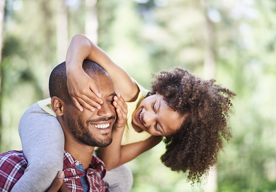 Playful Young Girl Covering Fathers Eyes