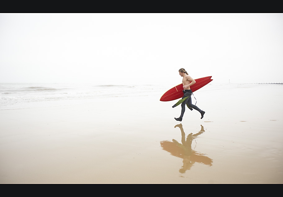 Male surfer running towards the sea